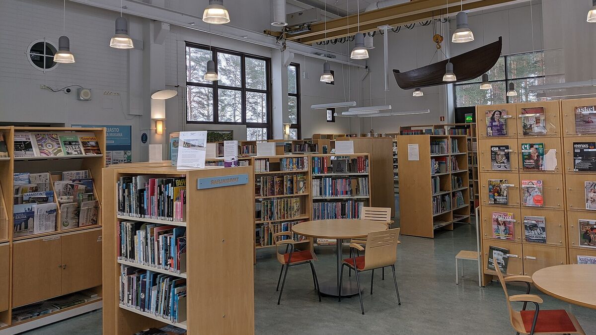 Bright small-town public library with bookshelves, magazine racks and round reading tables