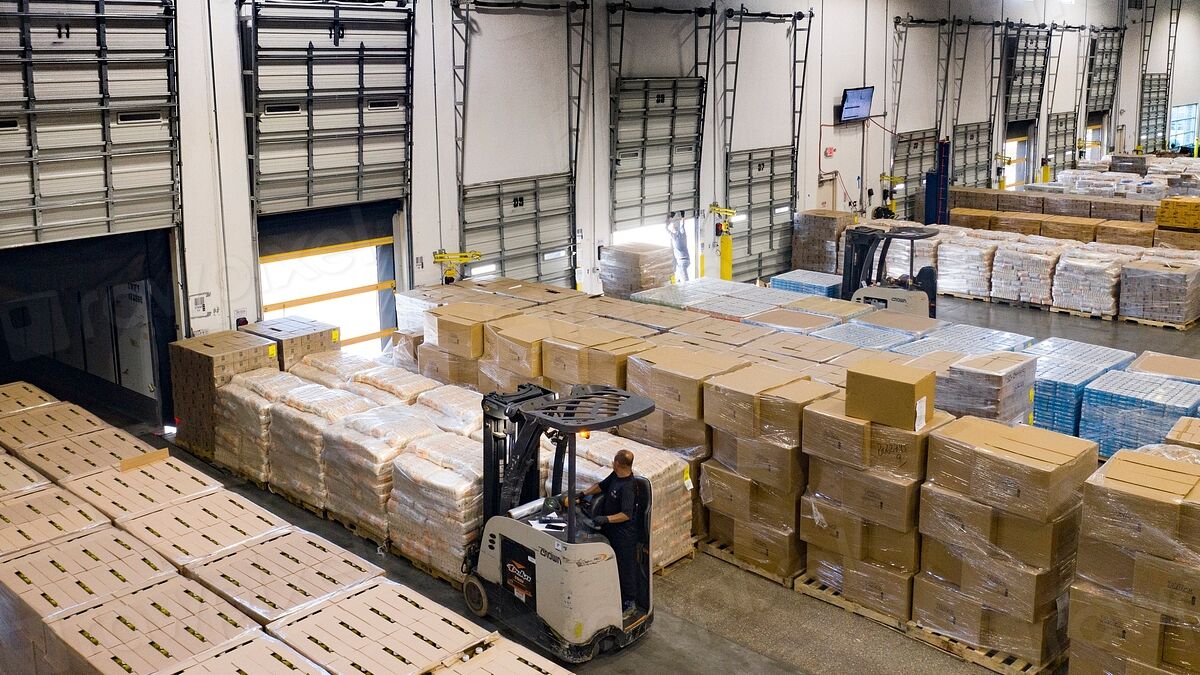 Food distribution warehouse with loading dock doors, pallets of boxed food and a forklift