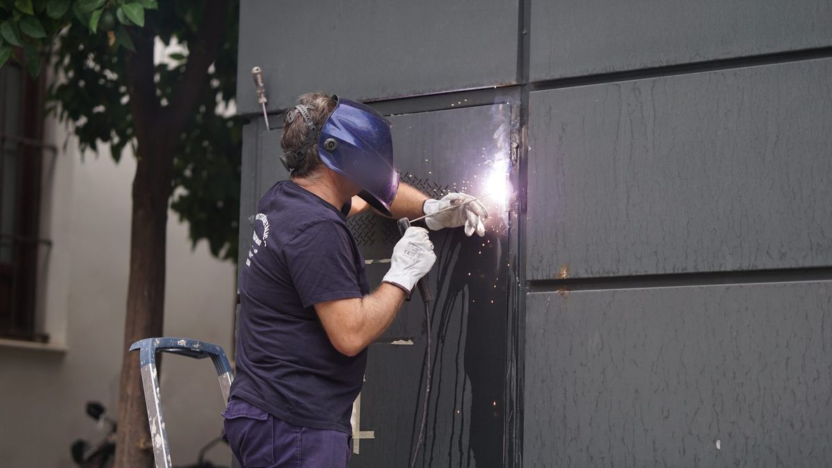 Worker in a welding helmet and gloves welding a steel panel